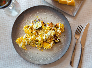 Fresh portion of fried eggs with pork pieces served on plate in restaurant