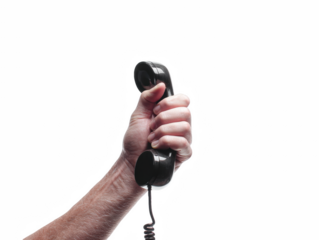 A hand grips a vintage black telephone receiver isolated on transparent background