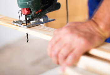 Work with an electric jigsaw - cutting a wooden board close-up