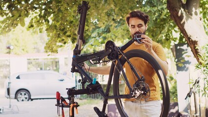 Young determined man checking bicycle parts in yard for damage that can be fixed with specialized...