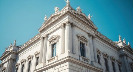 Fototapeta premium Architectural details of a historical neoclassical building showcasing columns and statues against a clear blue sky.
