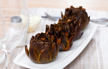 Top view of vegetarian appetizer of baked artichokes served on white plate
