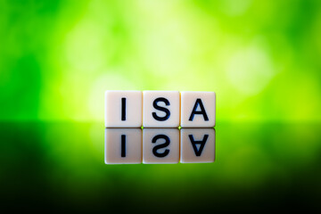 ISA abbreviation spelled with letter tiles on reflective glossy surface against vibrant green bokeh background symbolising UK tax-free savings.