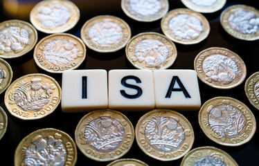 Individual Saving Account. Macro view of ISA cubes amid scattered pound coins forming money pattern...