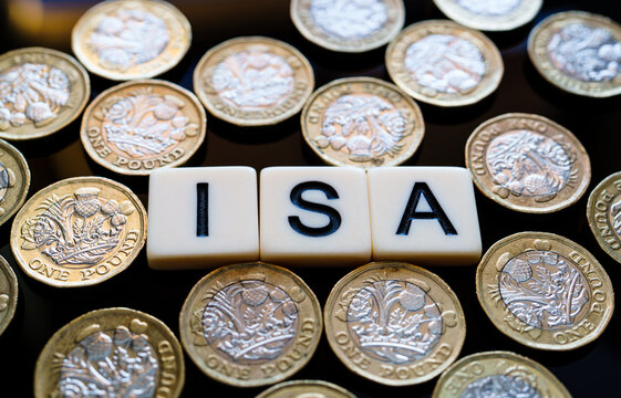 Individual Saving Account. Macro view of ISA cubes amid scattered pound coins forming money pattern highlighting UK tax free savings.