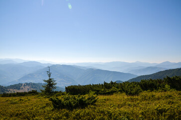 Beautiful mountain landscape featuring rolling hills, lush green shrubs, and tranquil sky. The...