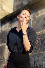 Portrait young adult elegant woman black dress and sunglasses blowing air kiss in golden sunlight...