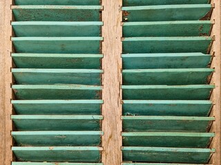 Old turquoise wooden window shutters showing signs of aging and weathering