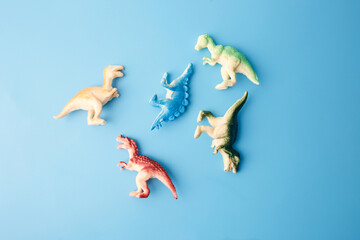 Colorful dinosaur figurines on blue background for toy catalog, kids education, preschool visuals,...