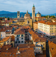Obraz premium Aerial view of Bergamo’s Città Alta in Italy with terracotta rooftops, historic churches, and mountain backdrop on a clear day