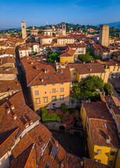 Naklejka premium Aerial view of Bergamo’s Città Alta in Italy with terracotta rooftops, historic churches, and mountain backdrop