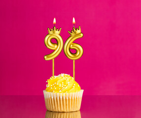 Yellow birthday cupcake with a number 96 candle - Birthday card on a pink background
