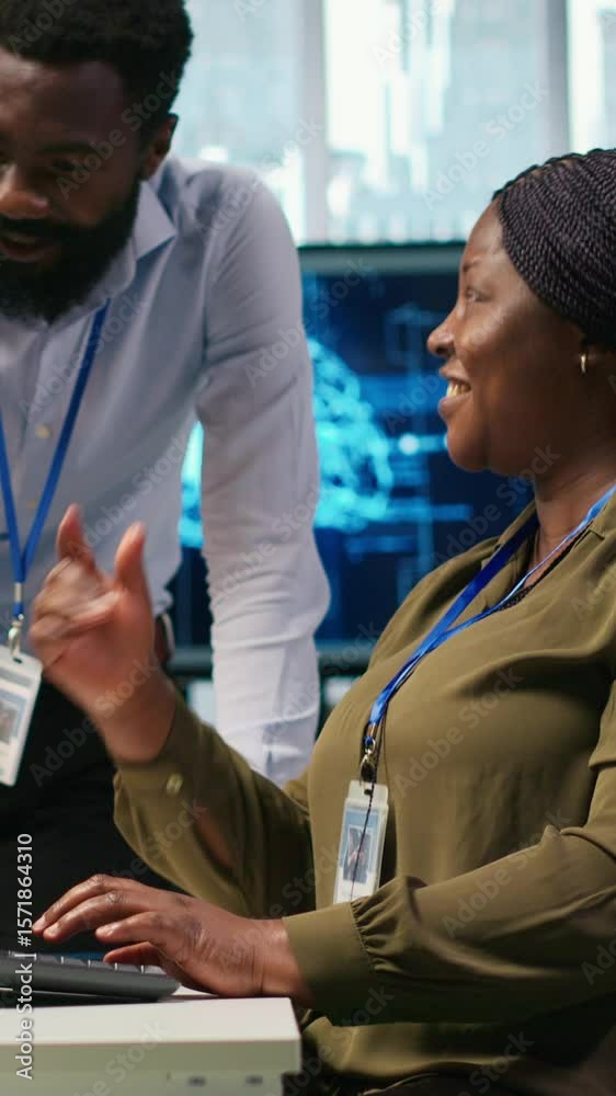Poster vertical video cheerful programmers in office enjoying conversation while automating repetitive task