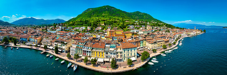 Aerial view of Salo, Italy with terracotta rooftops, lakeside promenade, and boats docked on the...
