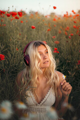 Naklejka premium Young beautiful blonde woman in headphones listening to music outdoors in summer