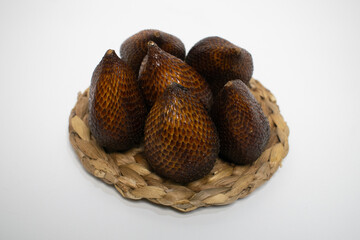 Salak with dark brown scaly skin displayed on a woven stand