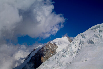 Naklejka premium Mont Blanc ascent views on snow-covered ridge, surrounded by alpine peaks under clear and cloudy sky. High-altitude mountaineering, glacier terrain, mountain landscape outdoor expedition in Alps