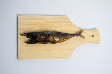 Whole fried fish placed on a light wooden board, ready to be served.