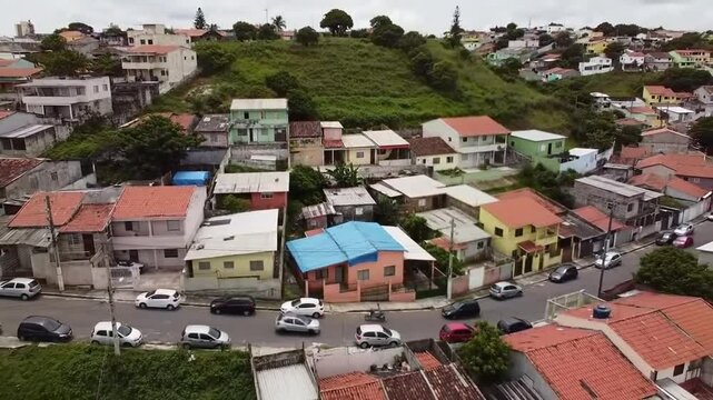 Aerial view of vibrant neighborhood with houses, cars and lush greenery on a hillside