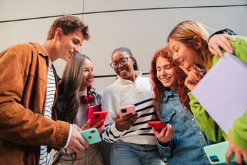 A lively group of teenagers eagerly engaging with their smartphones, sharing apps and experiences,...