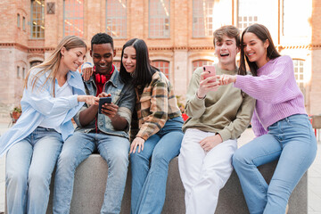 A group of enthusiastic teens enjoying their time together as they interact with their smartphones,...