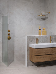 Contemporary bathroom with gold fixtures, marble walls, floating wooden vanity, and rainfall shower...
