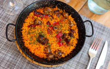 Appetizing traditional Valencian rice paella with snails served on platter