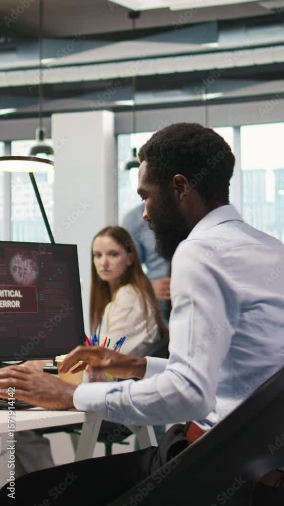 Poster vertical video programmer in office requesting help from coworkers to fix critical error warning. it