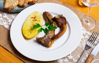 Appetizing grilled lamb spare ribs with baked potatoes garnished with greens