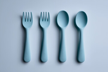 Fototapeta premium Pastel blue silicone fork and spoon set for toddlers, displayed neatly on a plain background. Designed with safety and comfort in mind. Suitable for parenting, food education, and product ads.