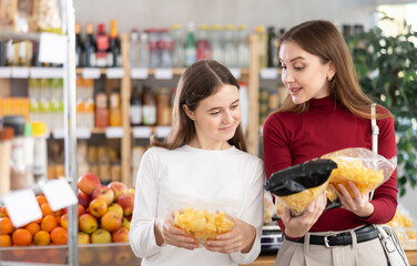 Mom and teenage daughter choosing potato chips and crispy mixes at the grocery store