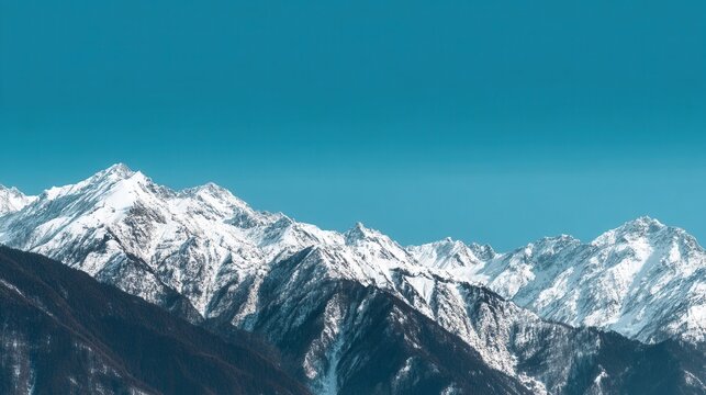 Snowcovered mountain peaks rise against a clear blue sky