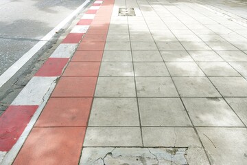 Concrete paver sidewalk, red white curb and road perspective view texture background
