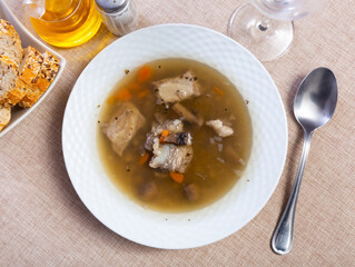 Service plate containing pearl barley soup with pork and mushrooms with necessary table laying