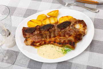 Appetizing grilled beef spare ribs with vegetable garnish of baked potatoes and piquant sauce....