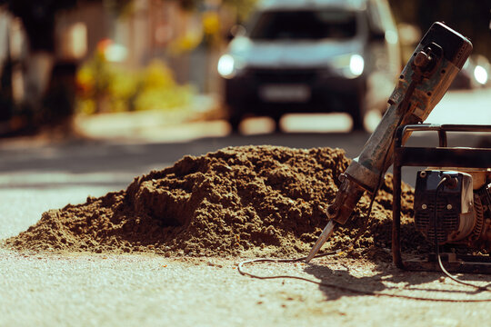  Demolition hammer on a Road Construction Site After a Day of Work. Heavy machinery resting on the side of a street 