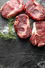 Pieces of raw beef meat and spices on dark table, flat lay. Space for text