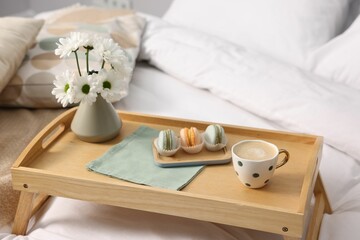 Tray with delicious breakfast and flowers on bed indoors, closeup. Space for text