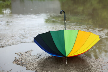 Colorful umbrella on wet asphalt under heavy rain. Space for text
