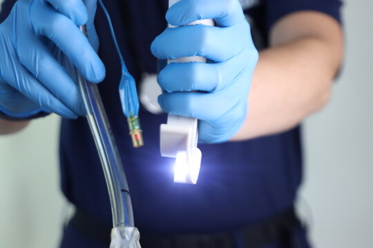Woman paramedic professional wearing surgical gloves holding a disposable laryngoscope with blade