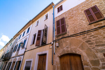 Fototapeta premium A narrow, old street in a Mediterranean country. Wooden doors and windows with wooden shutters, and balconies. Alcúdia, Mallorca, Balearic Islands, Spain. An island in the Mediterranean Sea. 