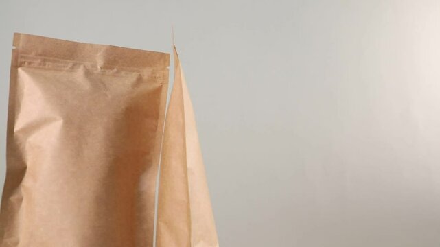 Zipper stand-up pouches spinning on light grey background, closeup. Space for text