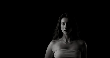 Dramatic black and white portrait of a young woman with half her face illuminated, creating a sense...