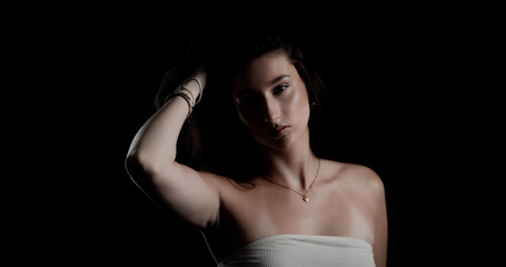Fototapeta premium Studio portrait of a young woman holding her hair on a black background
