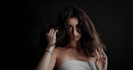 Fototapeta premium Studio portrait of a young woman playing with her long brown hair