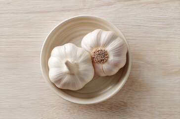 Garlic cloves in a white ceramic bowl on a white table backdrop with beautiful sunlight highlighting the scene