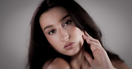 Fototapeta premium Beauty portrait of an attractive young woman with perfect skin touching her face