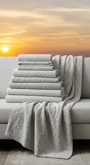 Stacked Gray Towels and Blanket on a Couch with Sunset Background