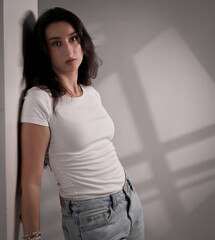 Portrait of a young woman leaning against a wall, wearing casual clothes, with a pensive expression