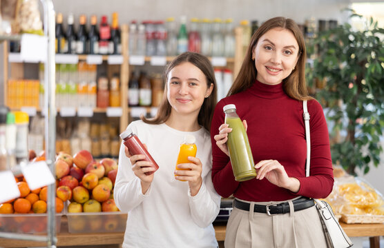 Happy mother with daughter in the supermarket choosing natural juices and smoothies for a healthy lifestyle
